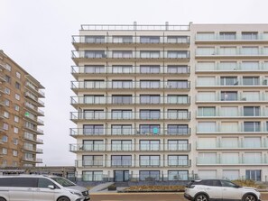 A multi-story residential building with balconies, a staircase, and a parking area with cars. - Apartment on the 9th floor with sea view (Middelkerke)