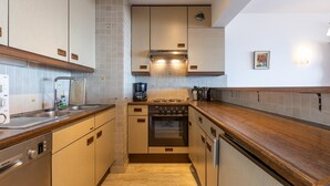 Eine moderne Küche mit Holzschränken, einem Bosch Geschirrspüler, einem Gasherd und einer Kaffeemaschine.