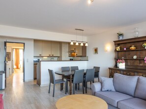 A modern kitchen with a central island, dining area with chairs, and a sofa. - Spacious apartment with garage and sea view (Middelkerke)