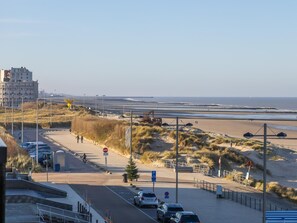A coastal road with a beach in the background, featuring a pedestrian path, parked cars, and a no-entry sign. - Corner apartment with frontal sea view (Middelkerke)