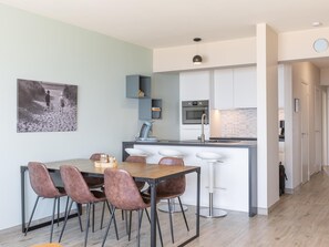 A modern kitchen with a central island, bar stools, and a dining table with chairs. - Apartment on the 5th floor with sea view (Middelkerke)