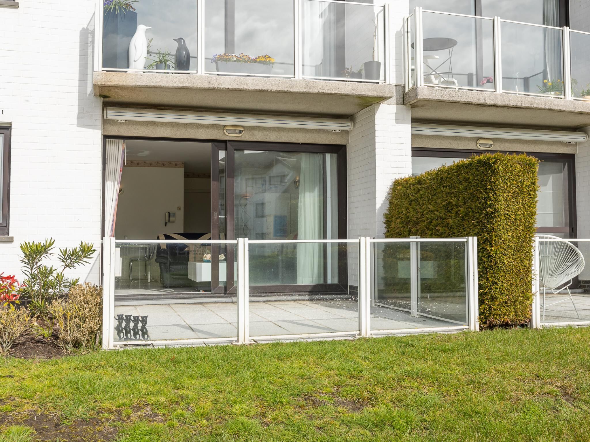 A modern two-story building with large glass windows and doors, a flat roof, and a well-maintained lawn.