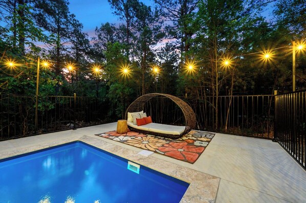 A pool area with a lounge chair and a decorative rug.