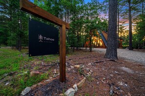 A sign for Tahoe in the Pines, surrounded by a forest with a cabin in the background.