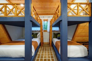 A dormitory room with bunk beds, wooden beams, and a tiled floor.