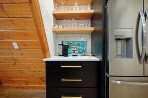 A kitchen with a stainless steel refrigerator, wooden shelves, and a coffee machine.