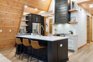 A modern kitchen with a central island, bar stools, and wooden paneling.