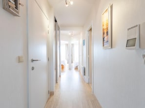 A hallway with a door on the left, a light switch, and a thermostat on the wall. - Apartment with 2 bedrooms and sea view (Middelkerke)