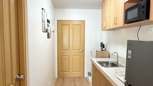 Una cucina angusta con mobili in legno, un forno a microonde, un lavello e un frigorifero.