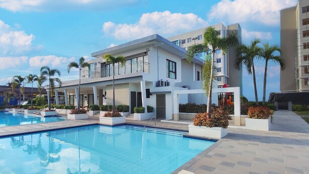 Un hotel moderno con piscina, numerosi balconi e palme.