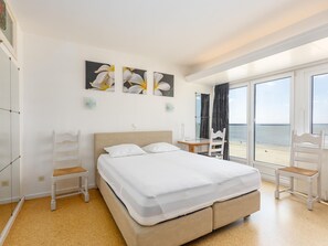 Une chambre d’hôtel avec un lit, un bureau, une chaise et une vue sur la plage.