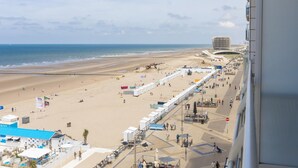 Ein Strand mit einer langen Promenade, einem modernen Gebäude und Blick aufs Meer.