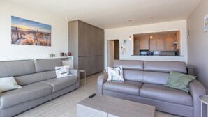 Ein modernes Wohnzimmer mit zwei Sofas, einem Couchtisch und einer Küche im Hintergrund.