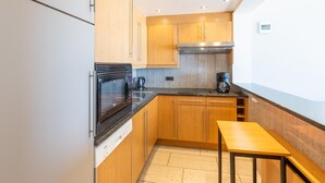 Eine moderne Küche mit Holdekor, einem Edelstahlbackofen, einer Kaffeemaschine und einem kleinen Tisch.
