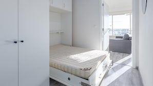 Une chambre moderne avec un lit, une armoire intégrée et une vue sur un balcon.