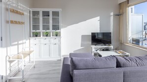 Un salon moderne avec un canapé gris, un téléviseur et un meuble blanc doté de portes en verre.