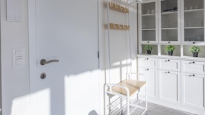 Une porte blanche avec une poignée, un porte-manteau avec des crochets et une petite table avec une chaise.