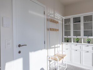 A white door with a handle, a coat rack with hooks, and a small table with a chair. - Modern, renovated studio with open views. (Middelkerke)