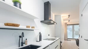 Una cucina moderna con mobili bianchi, un lavandino nero e una cappa aspirante in acciaio inossidabile.
