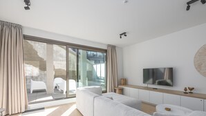 Un soggiorno moderno con un'ampia porta scorrevole in vetro, un televisore a schermo piatto montato sulla parete e un design minimalista.