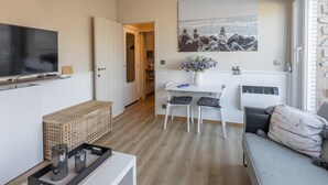 A modern living room with a TV, seating area, and a dining table. - Studio with sunny rooftop terrace near the sea (Middelkerke)