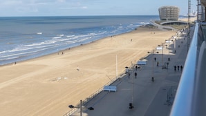 A beach with a modern building in the background. - Charming studio on the seafront with sea view (Middelkerke)