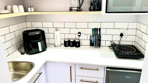 Une cuisine moderne avec des meubles blancs, une machine à café, une bouilloire, un four à micro-ondes et un lave-vaisselle.