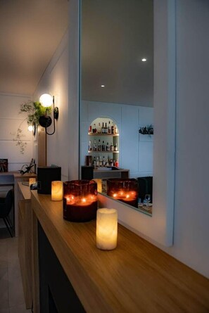 Zona de bar con mostrador de madera, velas y un espejo que refleja el bar.