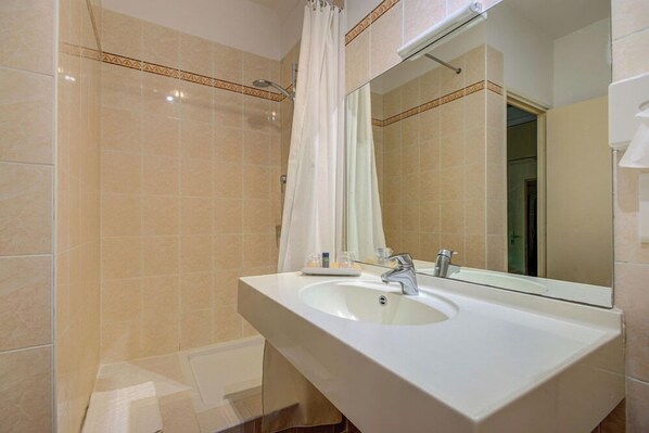 Ein Badezimmer mit Waschbecken, Spiegel, Duschvorhang und gefliesten Wänden.
