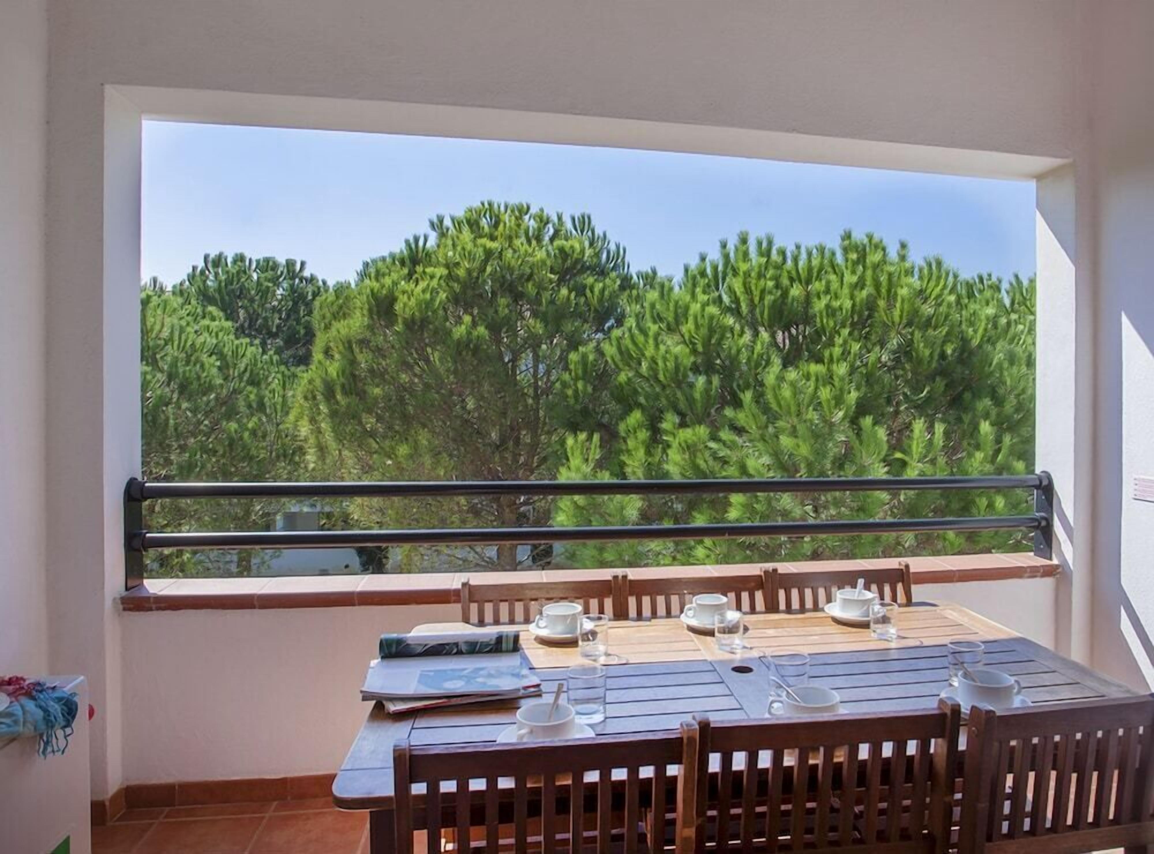Un balcon avec une table dressée pour deux personnes, donnant sur une forêt dense.