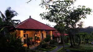A traditional house with a tiled roof, surrounded by lush greenery and a well-maintained garden. - Villa Capung Mas (Ubud)