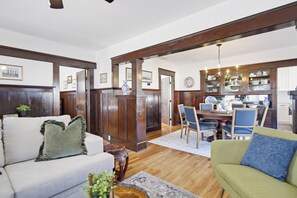 Ein geräumiges Wohnzimmer mit einem Holzesstisch, zwei Sofas und einer Pendelleuchte.