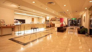 Vestíbulo de hotel con mostrador de recepción, cajero y zona de espera.