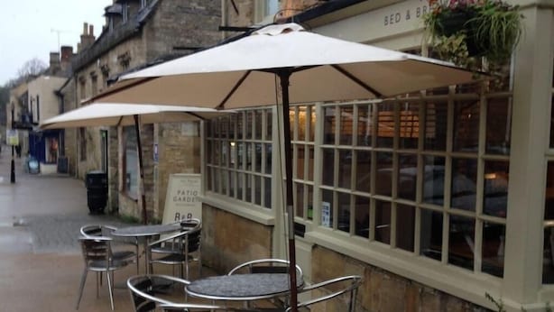 Un café con mesas al aire libre, un letrero que dice 'The Priory' restaurante y un letrero que indica 'Patio Garden'.