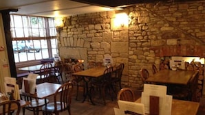 Un restaurante con paredes de piedra, mesas y sillas de madera.
