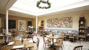Un restaurant chaleureux avec des tables et des chaises en bois, un menu écrit à la craie et un mur décoré de vieilles cartes postales.