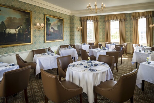 A formal dining room with round tables set for service, brown leather chairs, and classic blue and white china. - The Talbot Hotel (Malton)