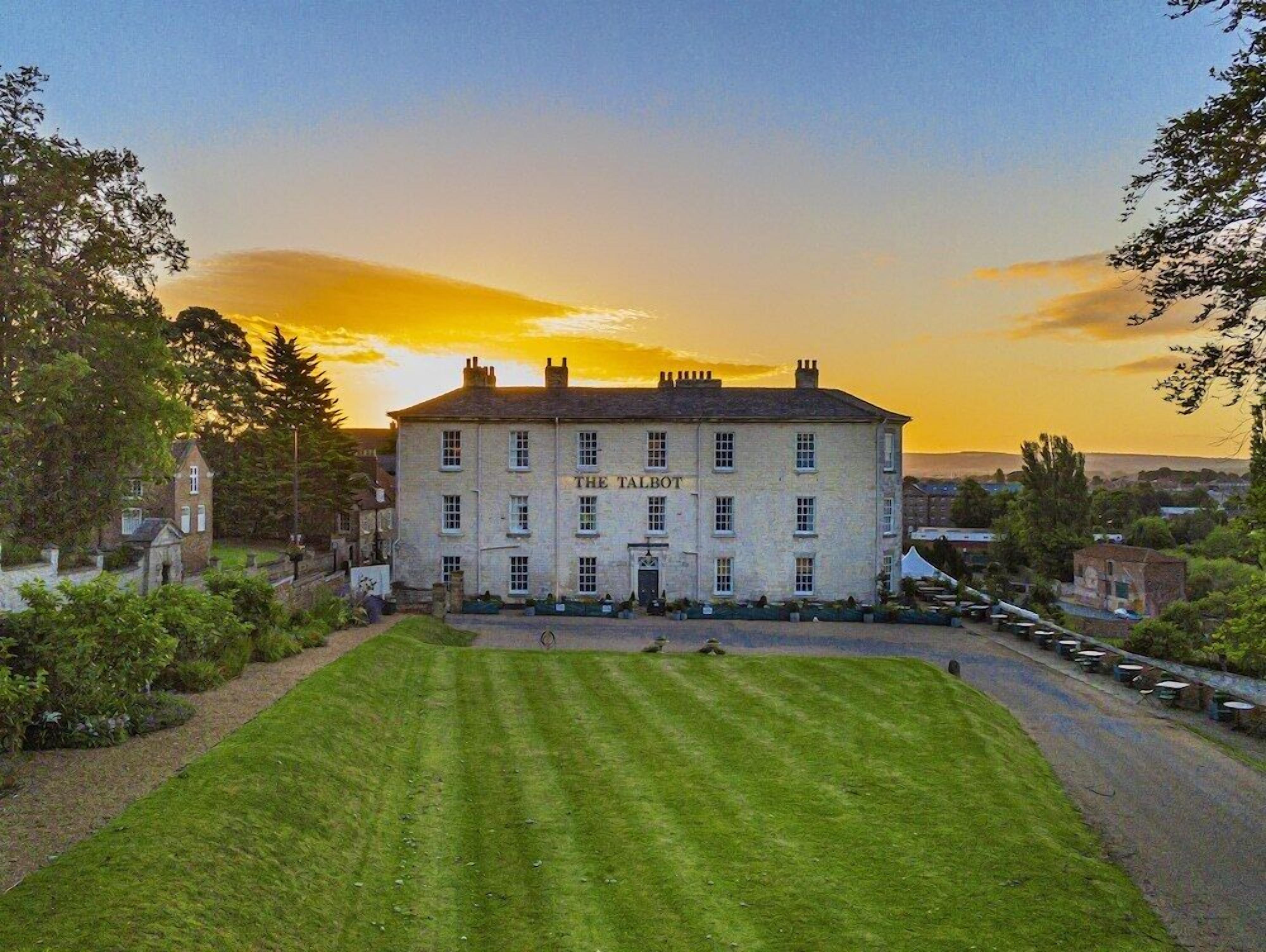 A two-story building named 'The Talbot' with a well-maintained lawn in front and a parking area to the right.