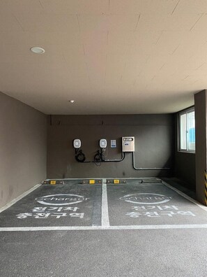 A parking garage with two charging stations and a window on the right. - I-check Hyunjin Hotel (Donghae)