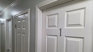 Un pasillo con puertas blancas, una de ellas con el número 1.