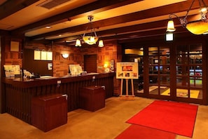 Un área de recepción con mostrador de madera, alfombra roja y una exhibición de fotografías.