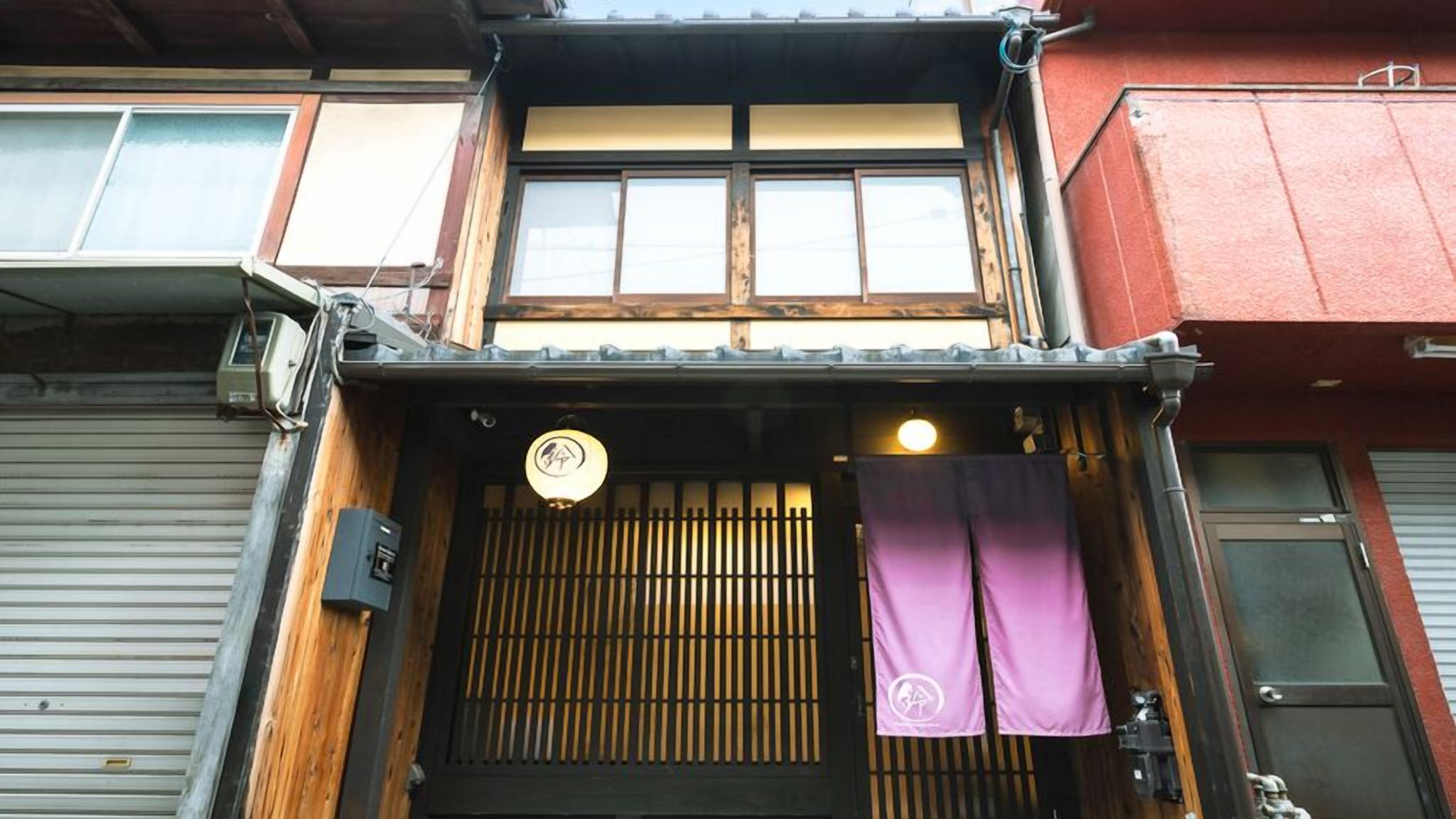 A traditional Japanese building with a wooden facade, a sliding door, and a small lantern.