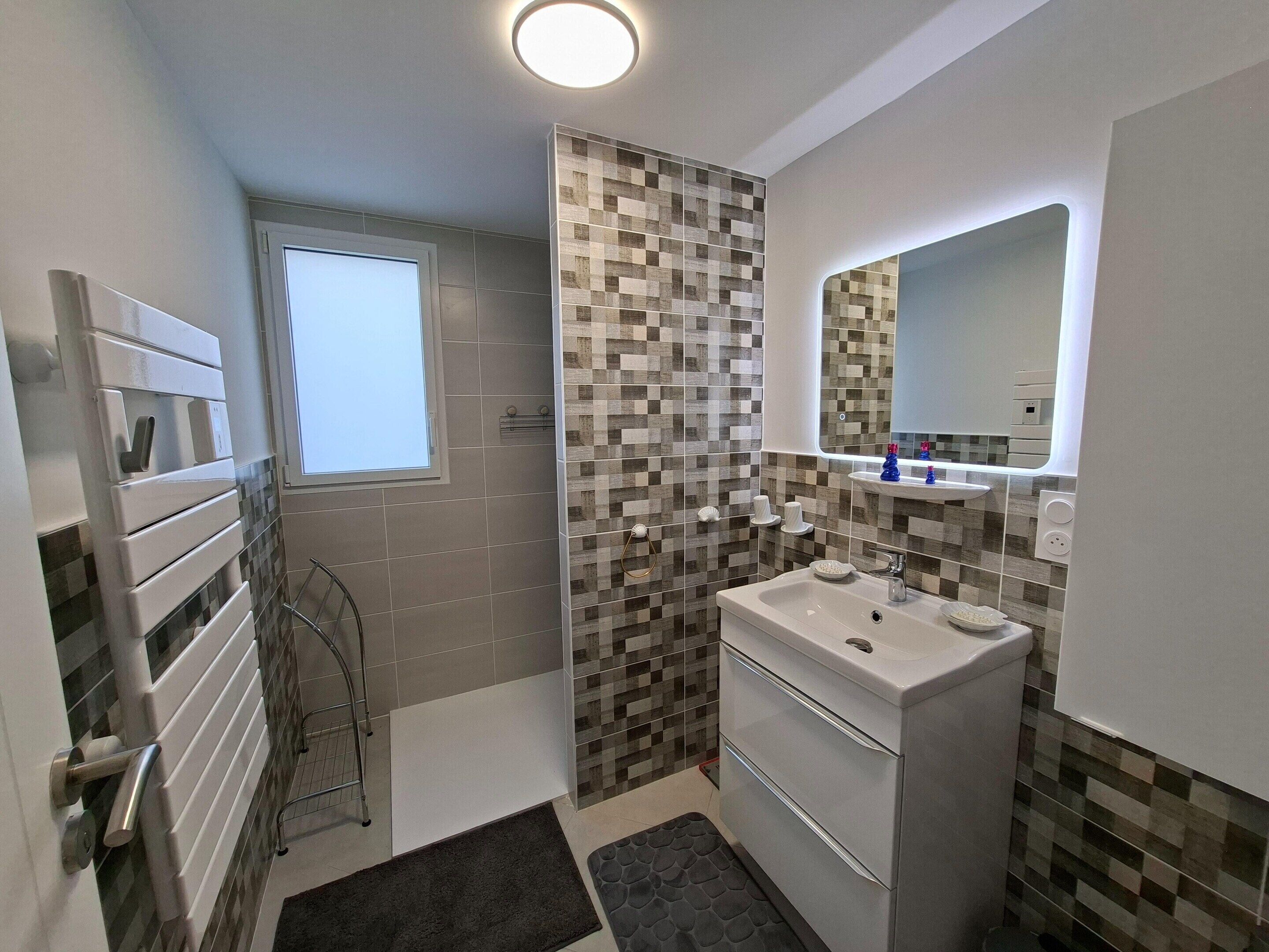 A modern bathroom with a checkered tile backsplash, a white sink, and a mirror above it.