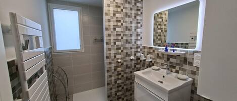 A modern bathroom with a checkered tile backsplash, a white sink, and a mirror above it.