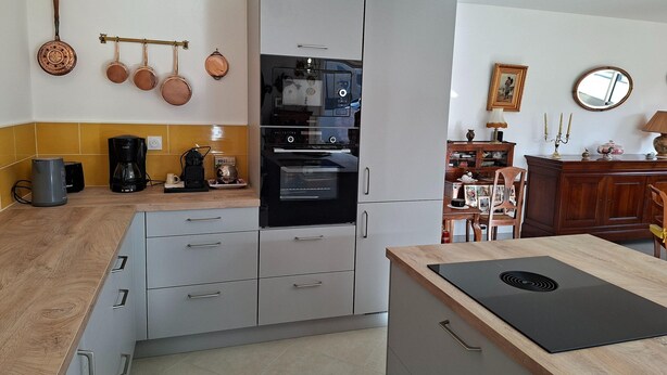 A modern kitchen with grey cabinets, a wooden countertop, a built-in oven, and a black induction cooktop. - Ground Floor Holiday Home in Plestin des Greves (Plestin-les-Greves)