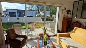 A living room with a sofa, armchair, and a coffee table with decorative items. - Ground Floor Holiday Home in Plestin des Greves (Plestin-les-Greves)