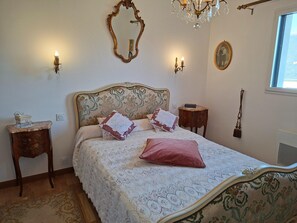 Une chambre à coucher avec un lit, un miroir, un lustre et une fenêtre.