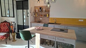 A modern kitchen with a wooden island, bar stools, and pendant lighting. - Ground Floor Holiday Home in Plestin des Greves (Plestin-les-Greves)