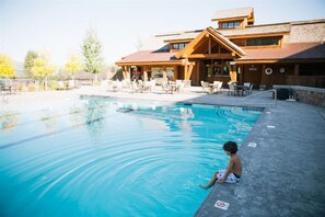 A swimming pool with lounge chairs and a wooden building in the background. - Teton Springs Lodge And Spa (Victor)