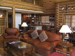 A cozy log cabin interior with a leather sofa, armchairs, and a coffee table. - Teton Springs Lodge And Spa (Victor)
